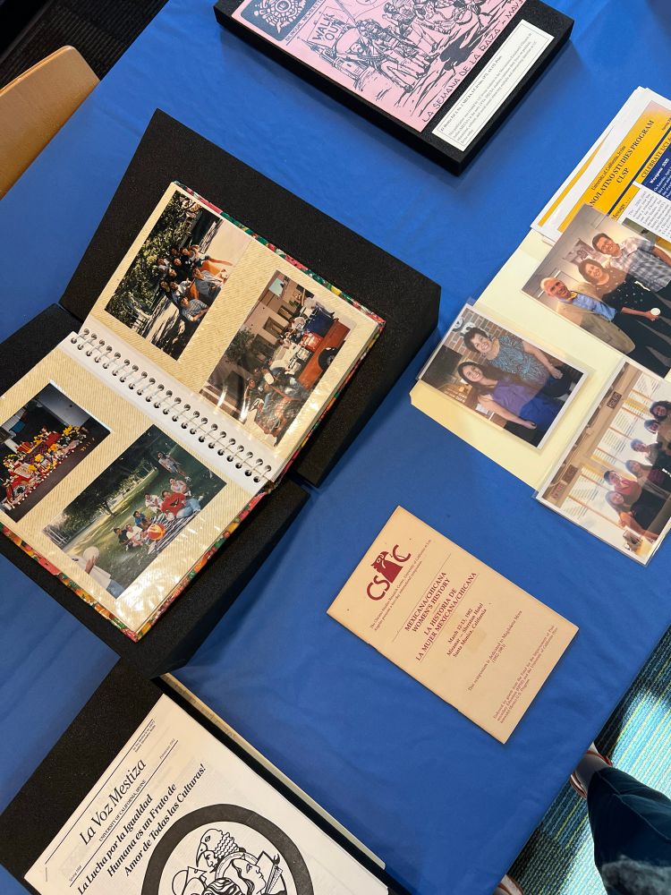 Materials from UC Irvine special collections & archives on a blue tablecloth background. Photographs and publications from a Chicano student organization, ephemera from faculty member Vicki Ruiz.