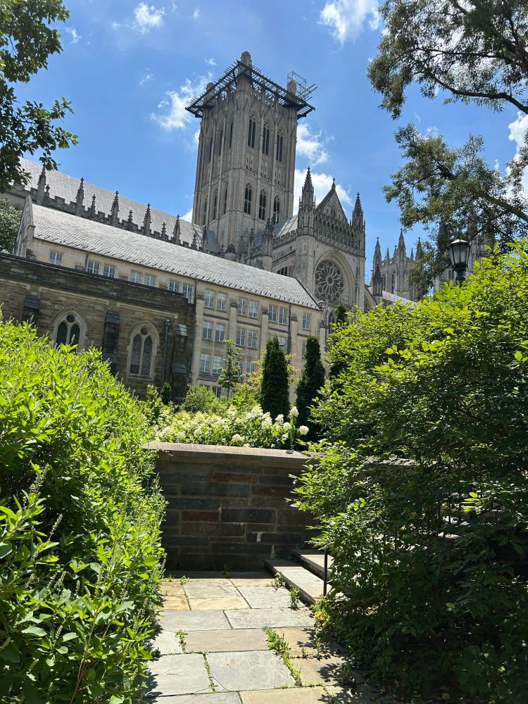 A view up the hill through a garden to the carillon bell tower of the National Cathedral in Washington, DC.