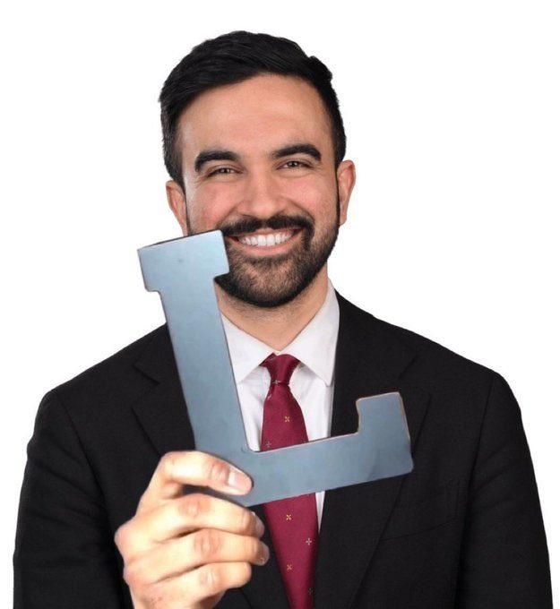 A hand holding an L superimposed onto a picture of Zohran Mamdani.