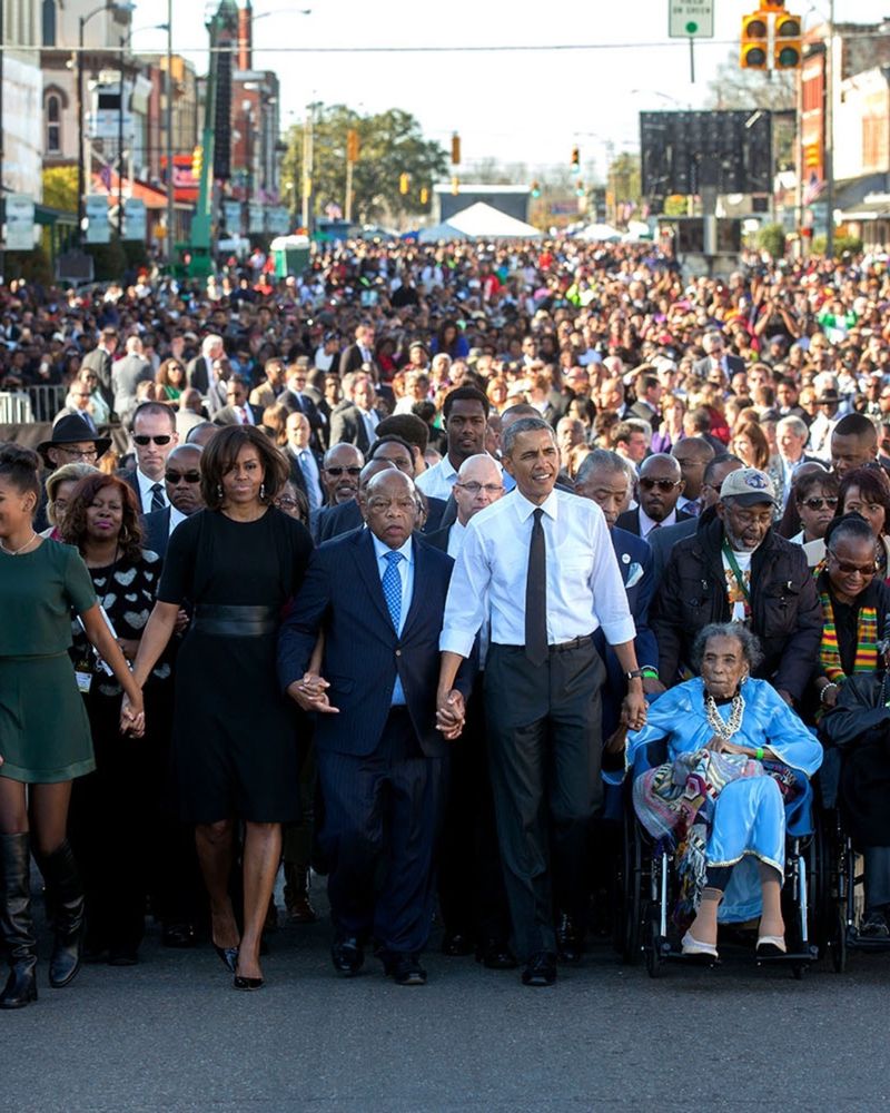 President Barack Obama and First Lady Michelle Obama join hands with Rep. John Lewis as they lead the walk across the Edmund Pettus Bridge.