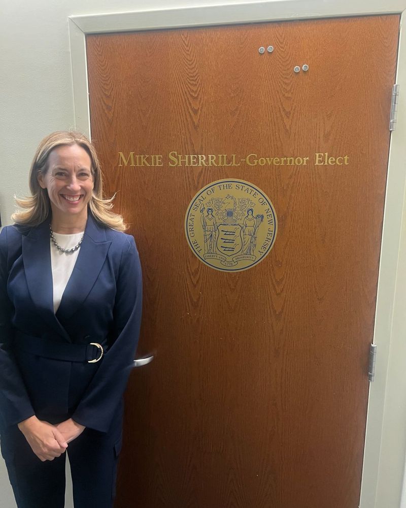 A photo of Mikie Sherrill in front of a door with the words "MIKIE SHERRILL - Governor Elect" on it.