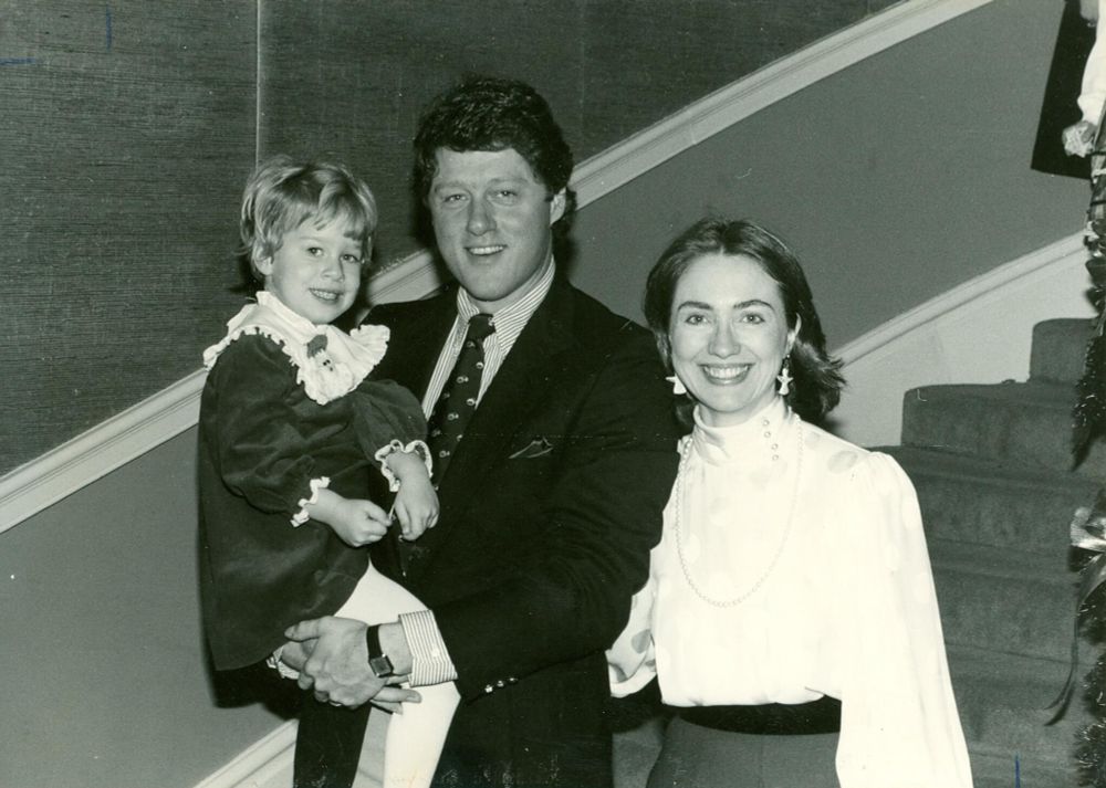 President Bill Clinton holding his daughter and standing next to Hillary Clinton.