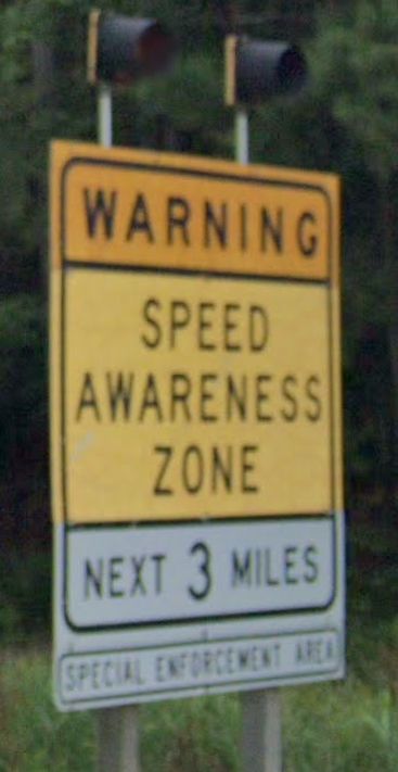 road sign with blinking lights on top
the sign says
WARNING
SPEED AWARENESS ZONE
NEXT 3 MILES
SPECIAL ENFORCEMENT AREA