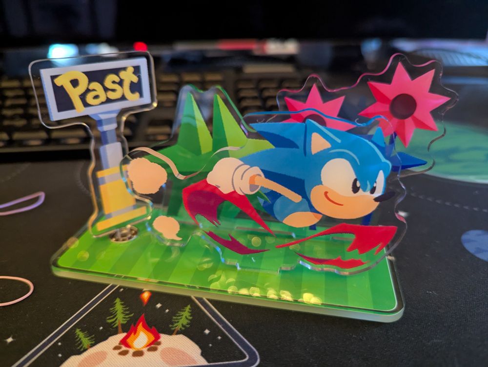 Sonic CD acrylic stand with Sonic running past a time travel sign (Past/Future) - which can be spun! It's a very close match to the official Classic artwork seen post-Mania.