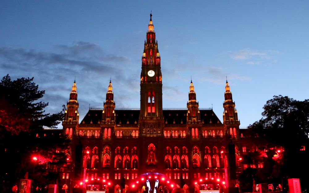 Das neogotische Wiener Rathaus, rot illuminiert anlässlich der Wiener Festwochen, in der Abenddämmerung
