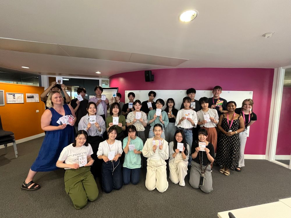 A group of students and teachers hold zines and smile 