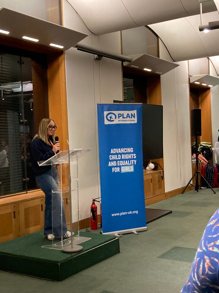 A young woman holds a microphone and speaks 