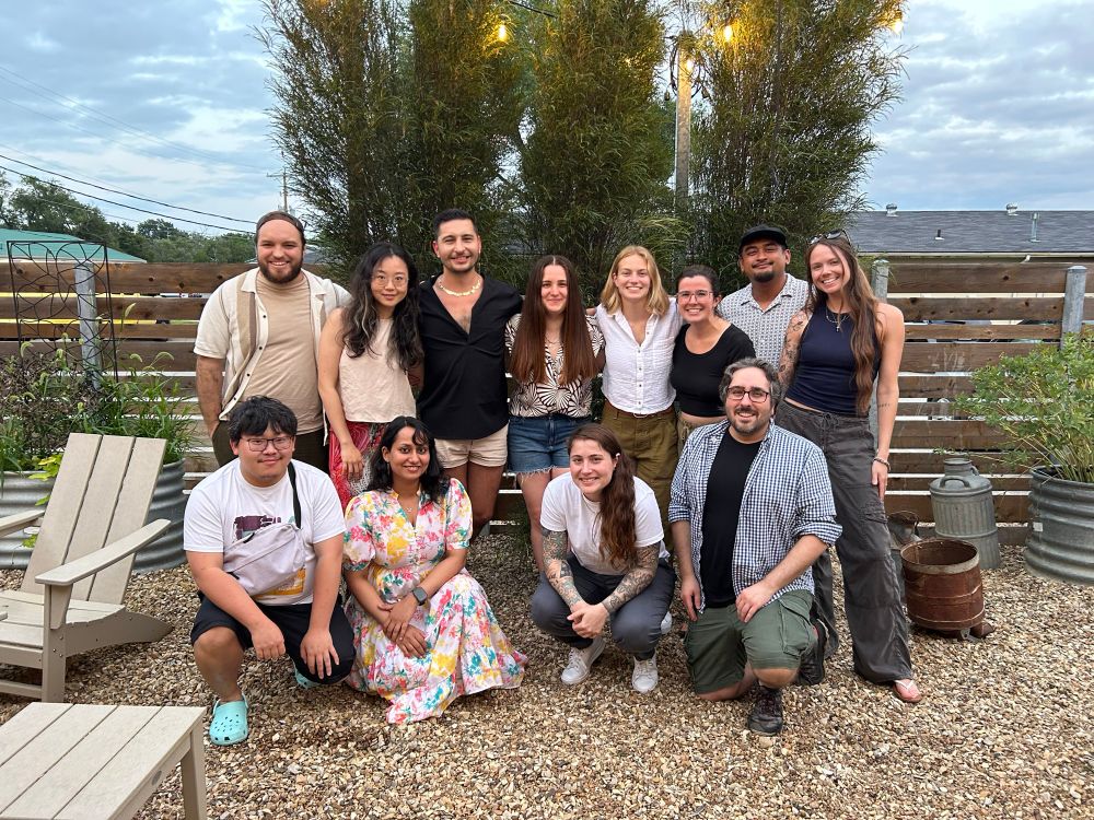 A group photo of Brett with colleagues from KU’s Department of Psychology standing in front of some plants and a fence outside at a brewery