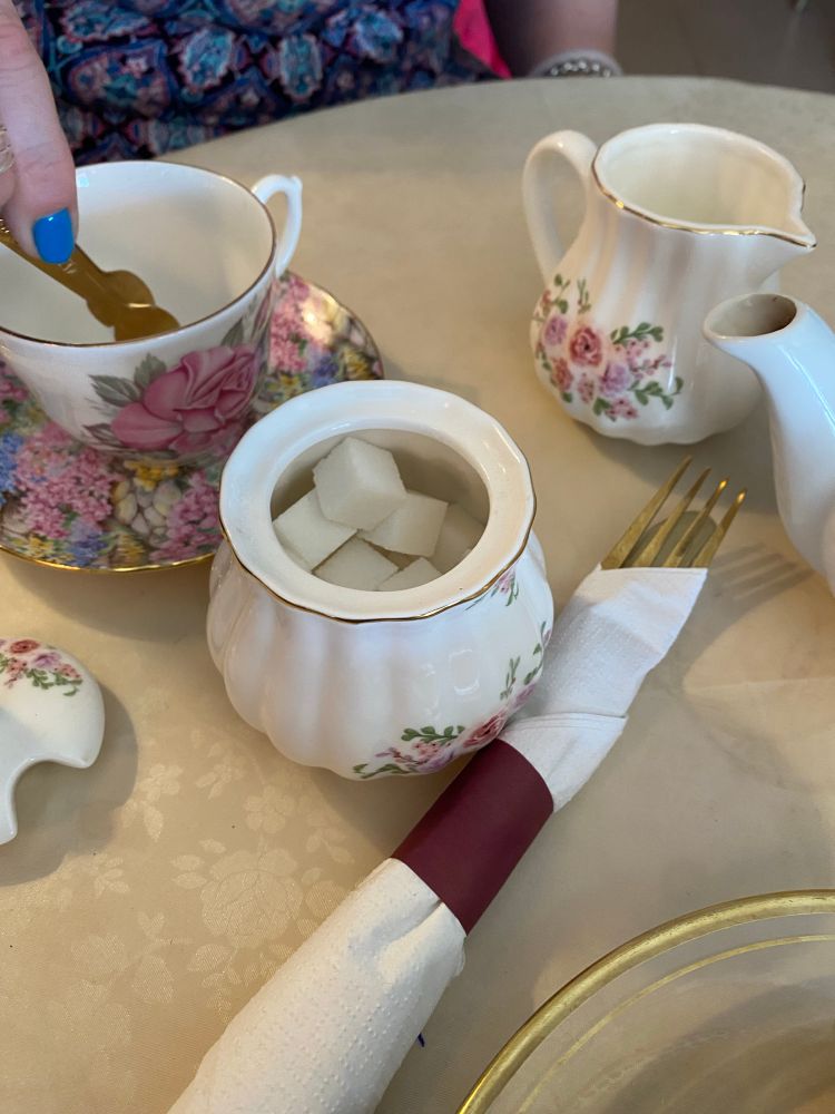 Table with a fancy floral china sugar cube bowl, matching teacups and teapot 