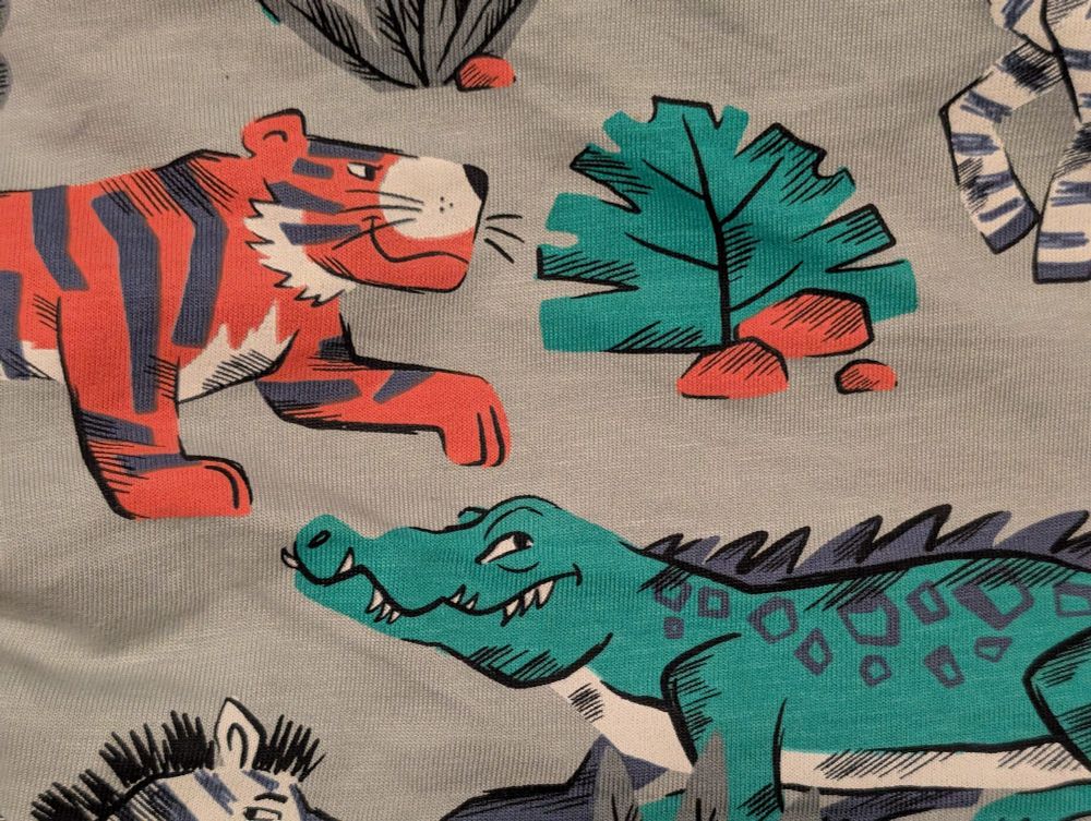 A cartoon tiger and aligator on a shirt with smirking faces.