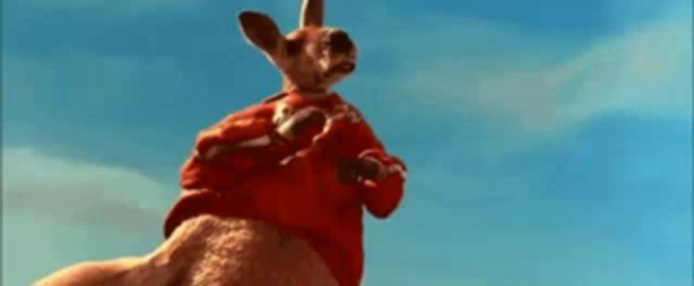 a kangaroo wearing a red shirt is standing in the air .