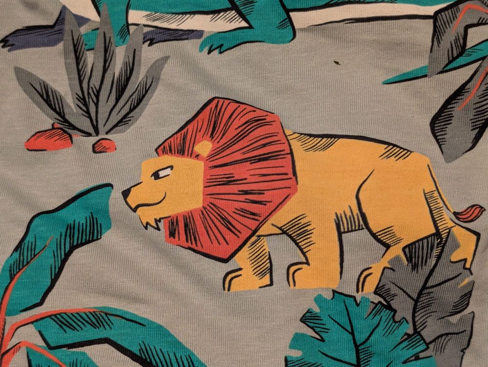 A cartoon lion on a shirt with a smirking face.