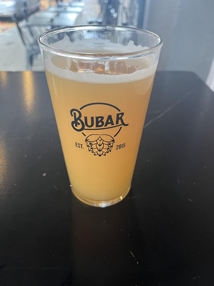 Une pinte de bière Neipa opaque couleur jaune orangé dans un verre décoré d’un bourgeon de houblon, d’un logo « Bubar » et du texte « établi en 2015 »