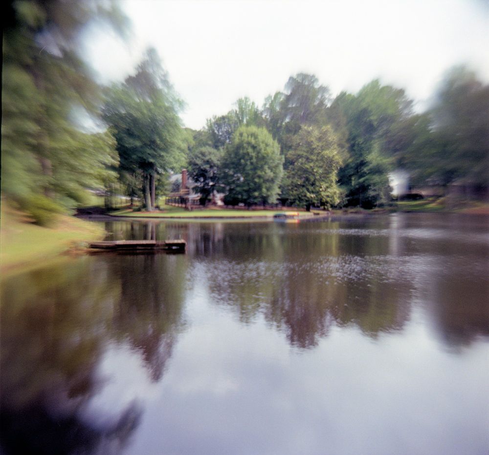 Photo of trees reflected in a lake, edges of the photo are distorted