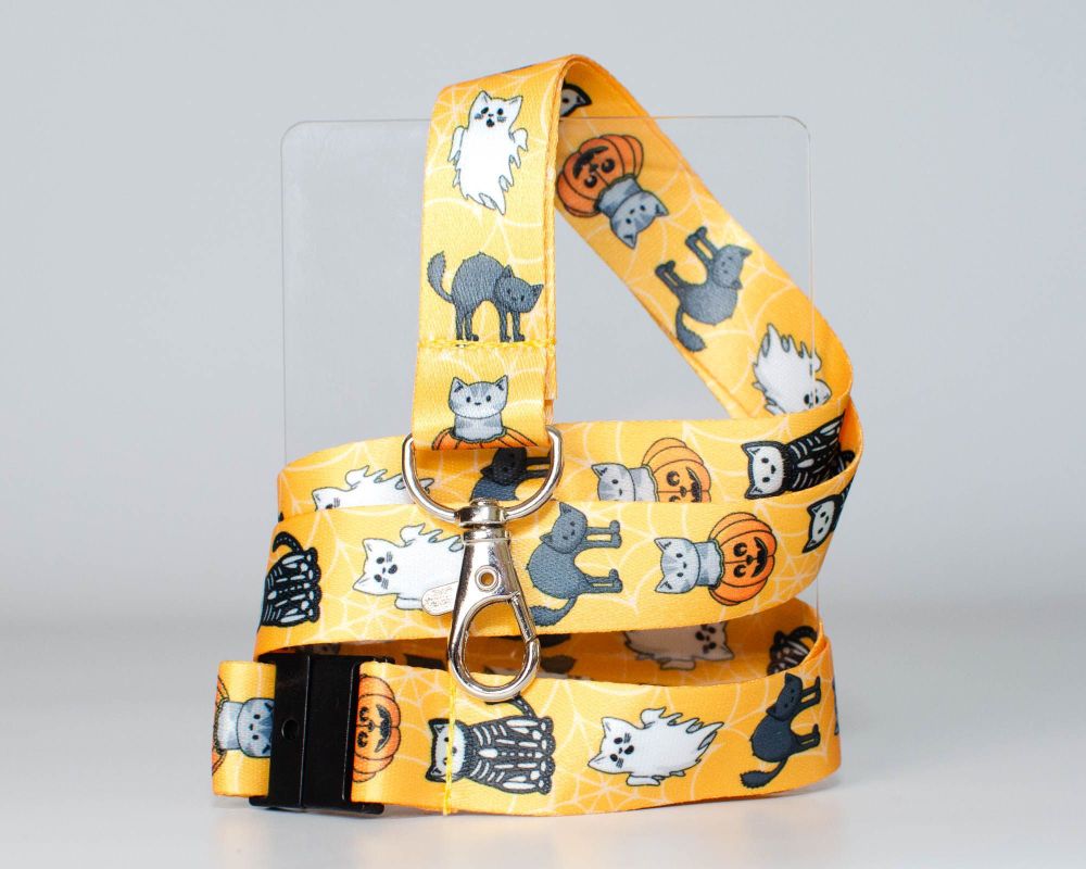 an orange lanyard with cartoon cats, one is a ghost, another is in a pumpkin, there's a skeleton cat and another with an arched back trying to look scary