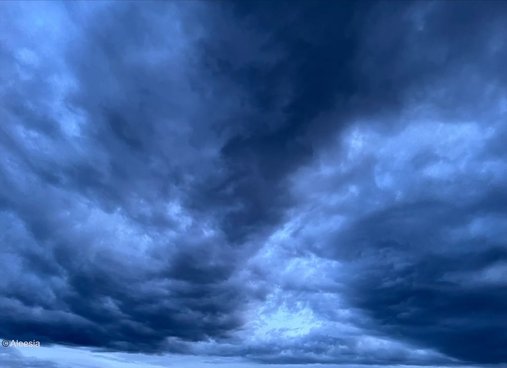 A bright beautiful sky during a storm. The clouds are several shades of blue and white.