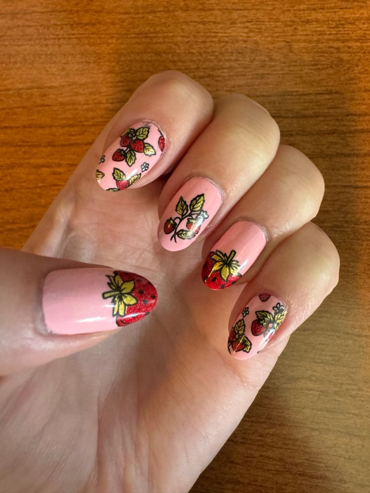 Pink nails with various strawberry designs. 