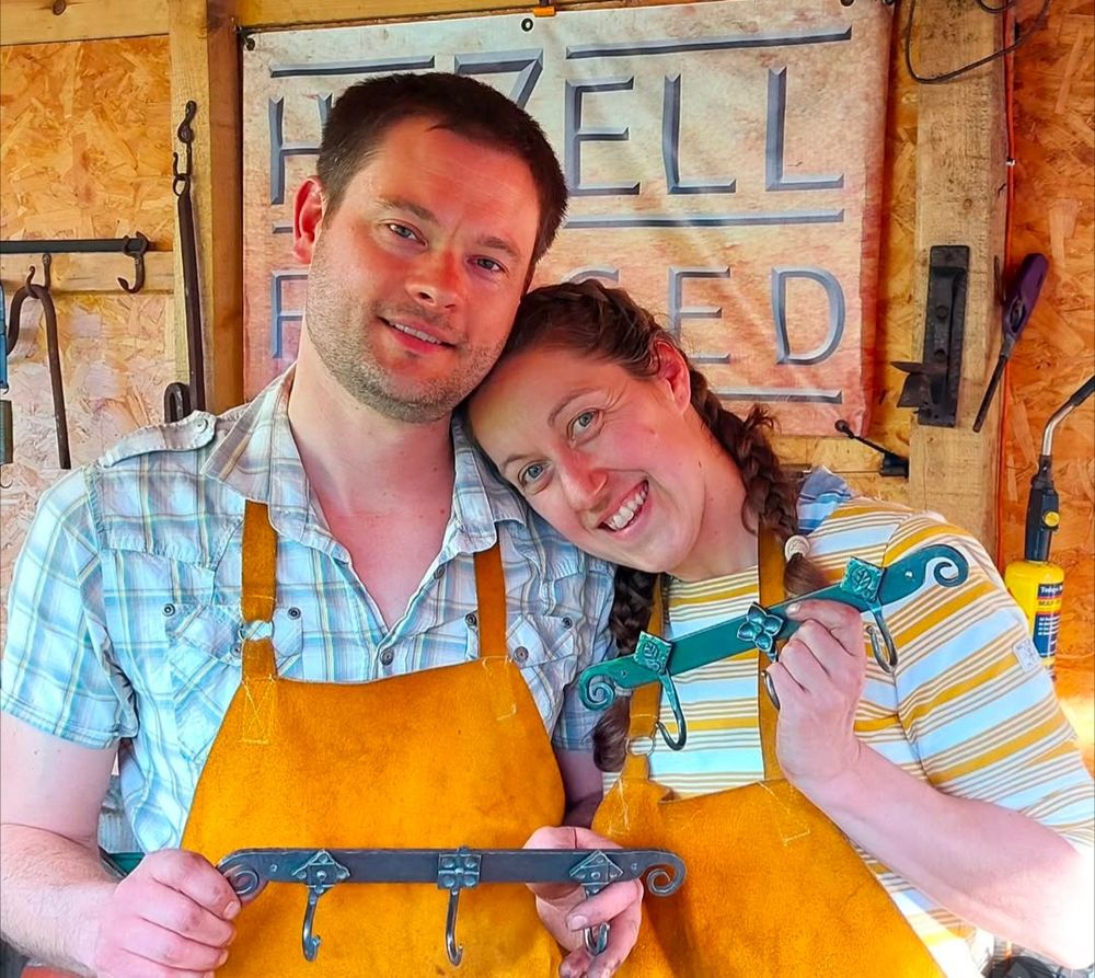 Photo of me in and Alec holding up coat hooks that we made ourselves wearing yellow aprons 