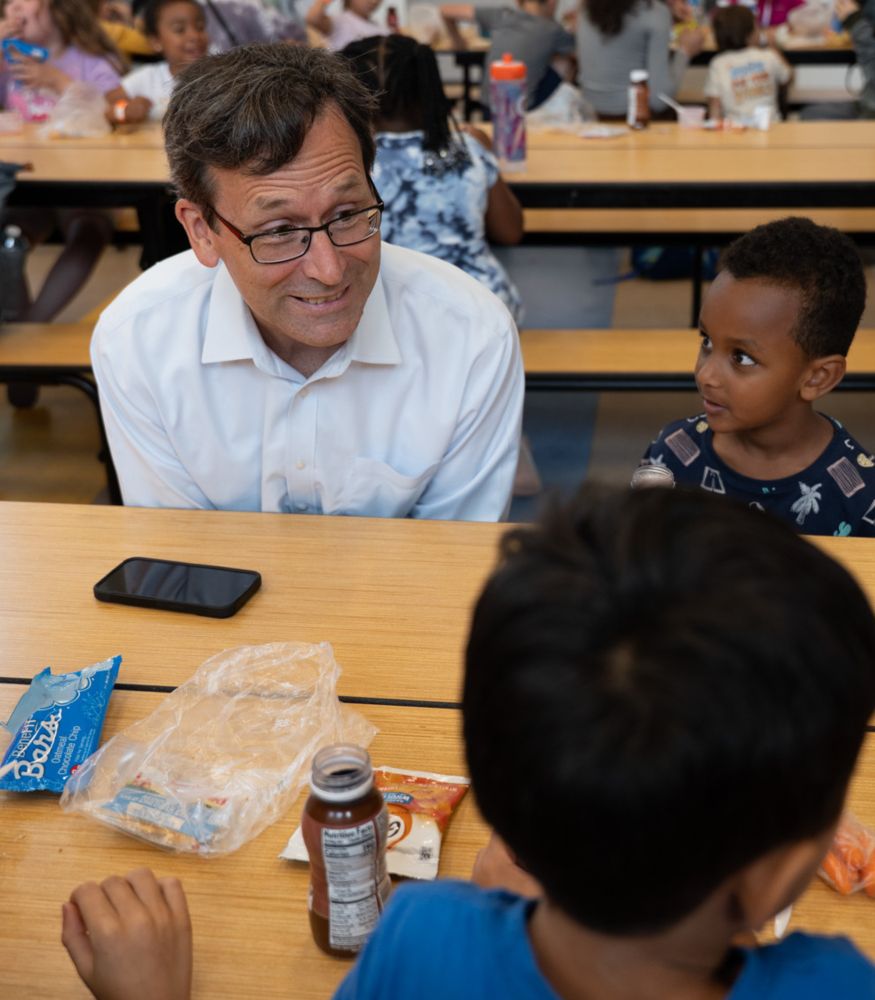 Bob at school lunch table with one kid next to him and another across the table 