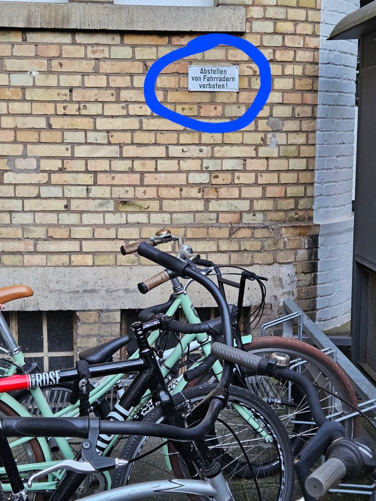 Hier ist erkennbar, dass das Schild mit der Aufschrift "Abstellen von Fahrrädern verboten" direkt über einem Fahrradständer hängt