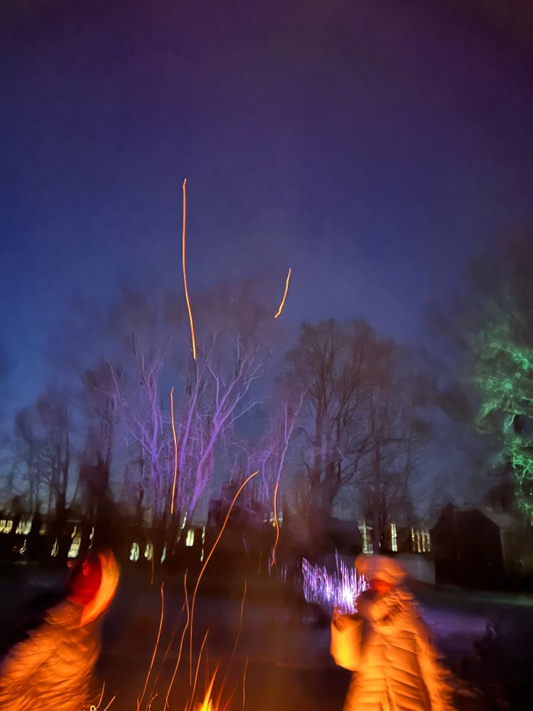Sparks from a fire pit dance in a night sky. 