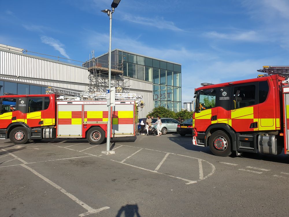 Two fire engines in the store carpark (with bonus image of me, or rather the shadow of my head, hands & phone)