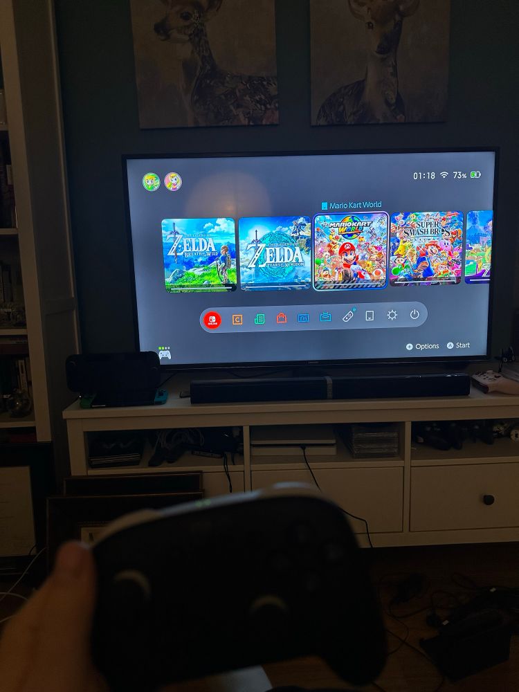 terribly lit TV screen with Mario Kart World downloading