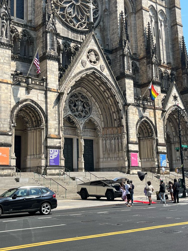 Stupid, janky, tiny-looking cybertruck in front of beautiful, enormous Cathedral of St John the Divine.