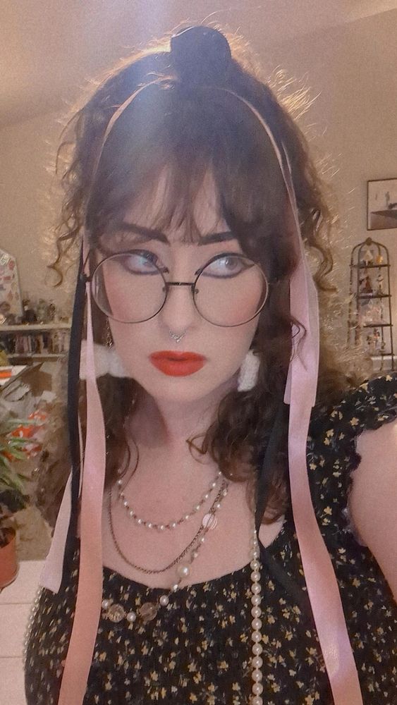 same look; i have ribbons dangling from my hair. i'm wearing layered pearl and bead necklaces. my eyes are rimmed with intense black winged liner and my lips are bright red.