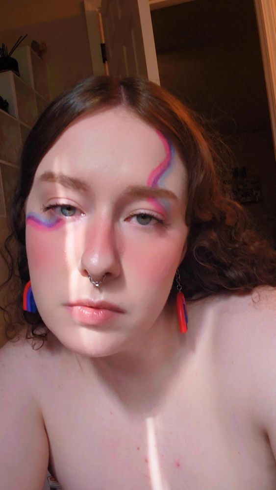 another photo of me wearing squiggly makeup in the colors of the bi pride flag.
