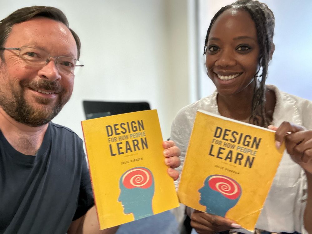 Jonathan and Thembi smiling at camera and holding up copies of Julie Dirksen's book Design for How People Learn.