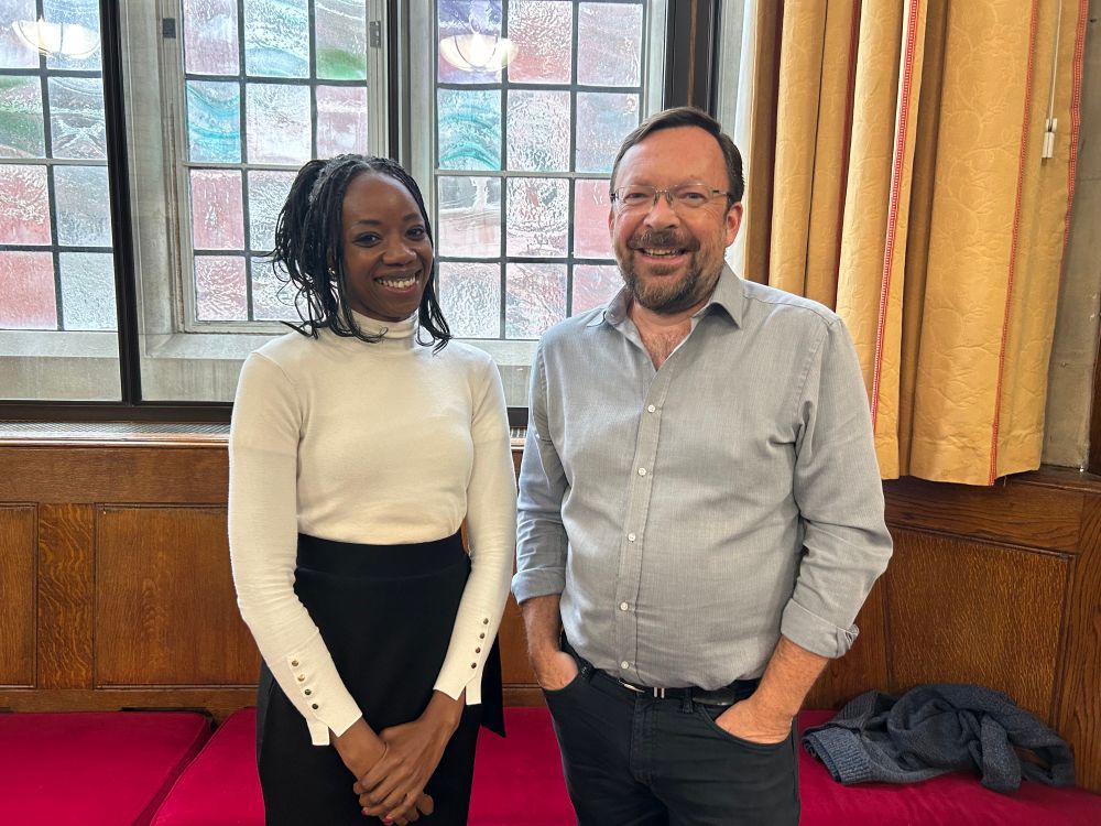 Photo of Thembi and Jonathan standing in a conference room and smiling at the camera