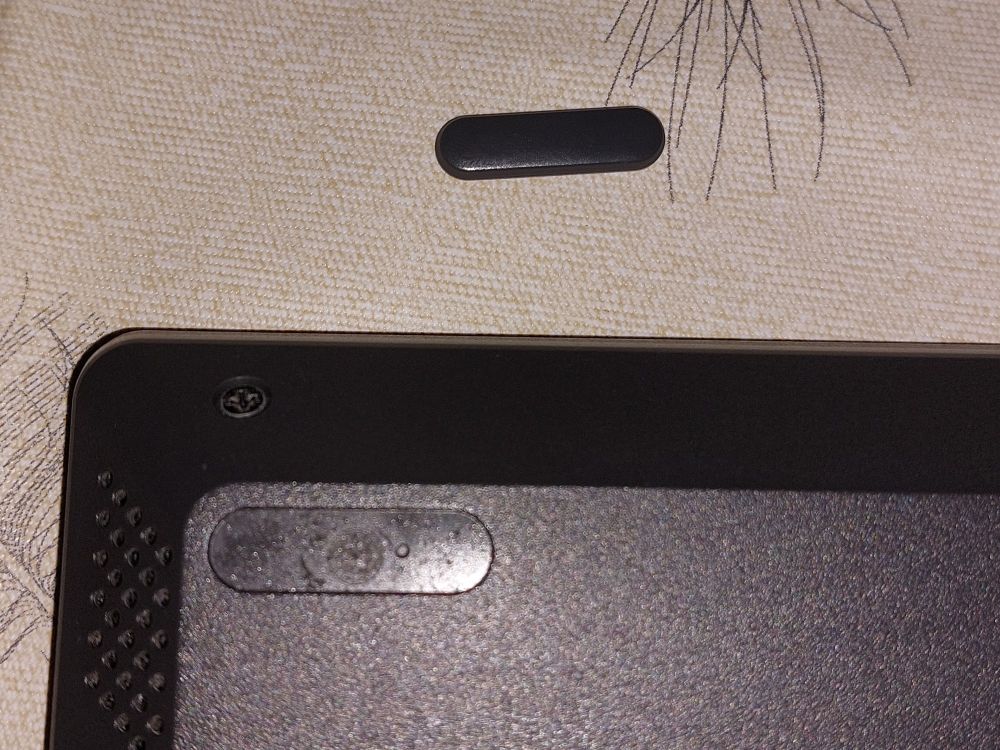 Back of a Lenovo IdeaPad laptop with some plastic underneath the plastic feet. The foot itself is placed on the table.
