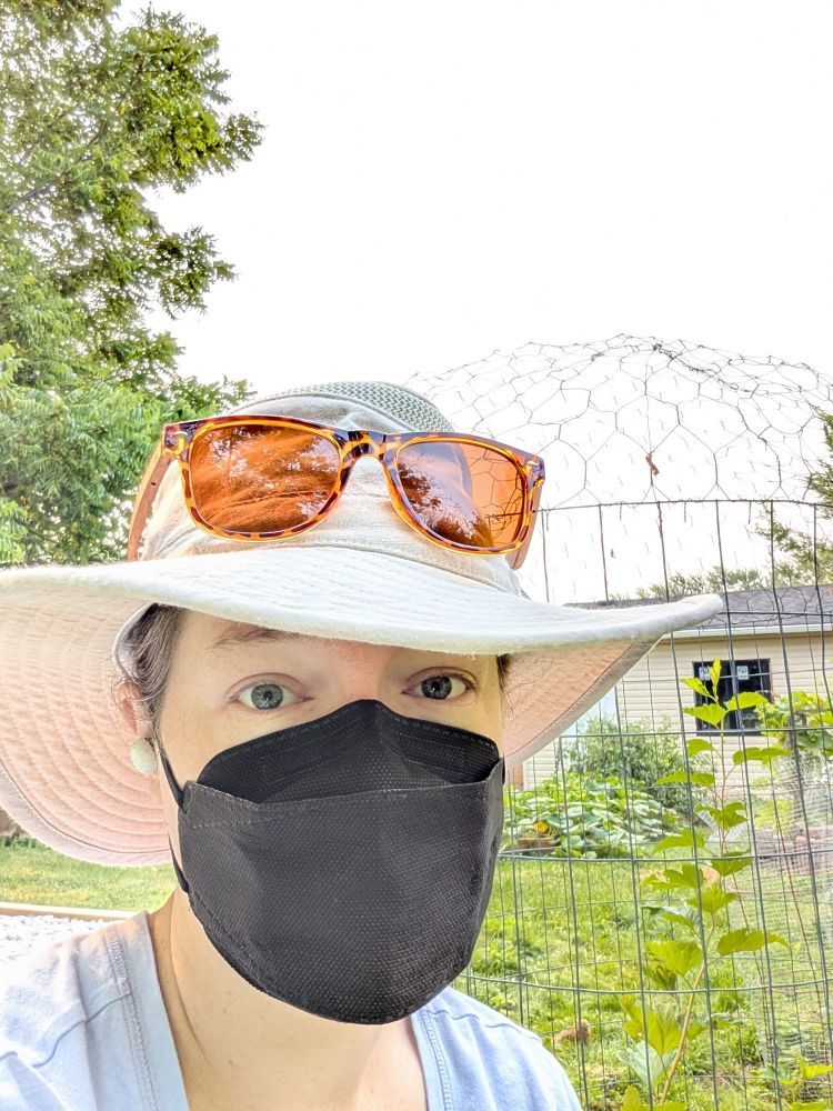 Close up of @n8rnerd in a black CAN95 mask and Tilley hat in the garden.