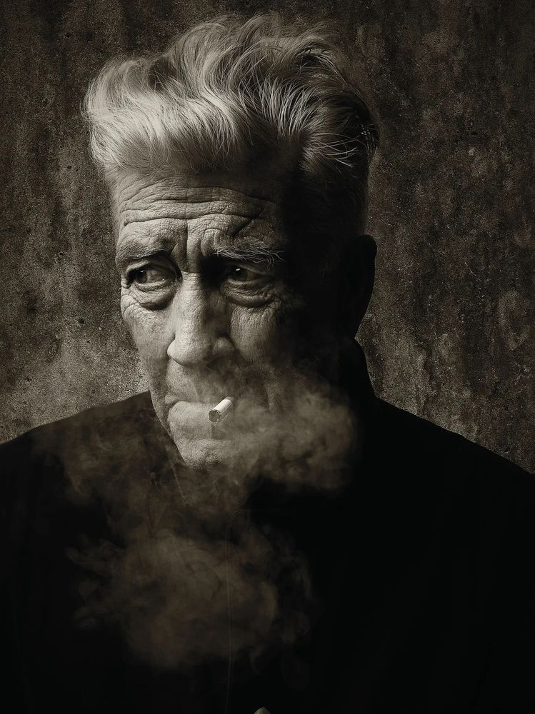 A sepia black and white photo of David Lynch smoking a cigarette. Photography by Sandro.