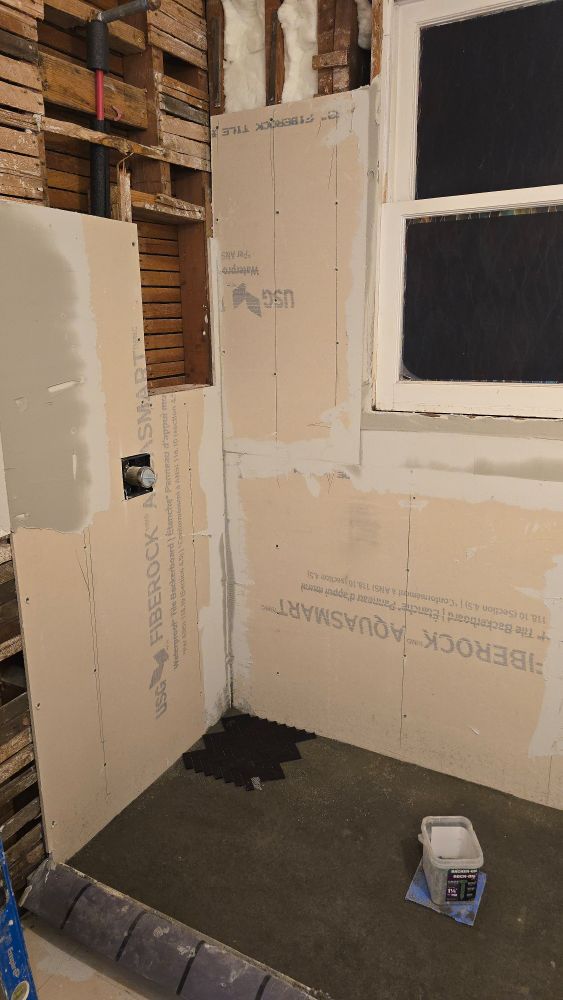 Showing the floor and part of the wall and the window. Between the valve and where the shower head goes, you can see the area they cut out for the niche. We couldn't center it on the back wall like sensible people because there's some old defunct ducting in the way but actually this will be more convenient.