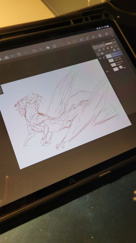 Photo of a tablet which is open to an art program. The art program shows a quick sketch of a unique dragon with wings for back legs, normal front arms, and a large rack of horns on its head. 