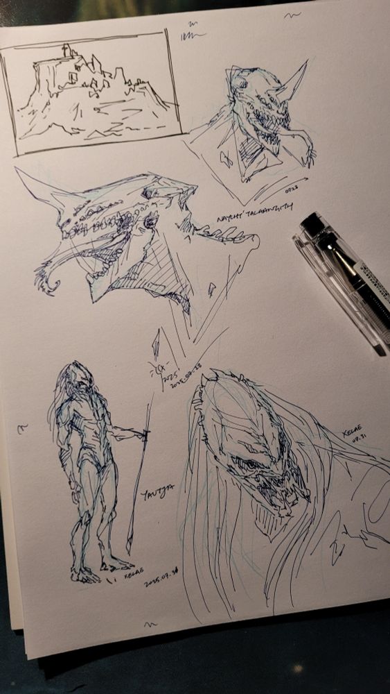 Photo of a few quick sketches done in pen. One in the corner is a small landscape of a hilly mesa. Two of the other drawings are headshots of a closed personal species called Naycht. Long head with spaced out flat teeth, two rows of multiple eyes, and a horn above its nose. No hair. Two of the other drawings of a Predator/Yautja OC. He has a longer, narrower skull. 
