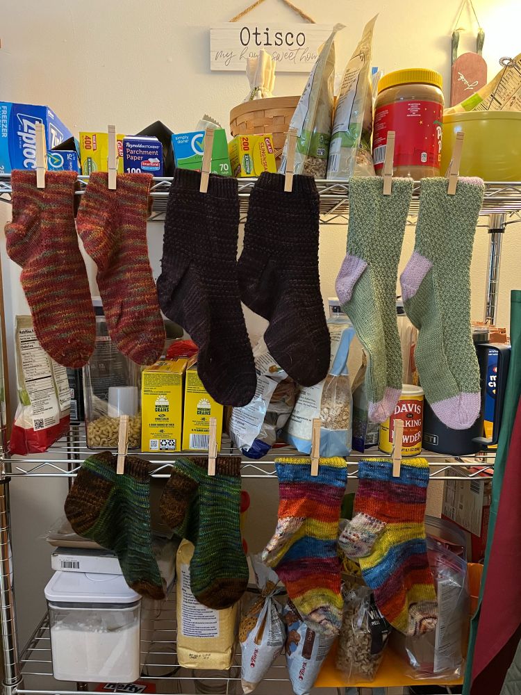 Five pairs of hand-knit socks drying on the pantry rack after washing! 