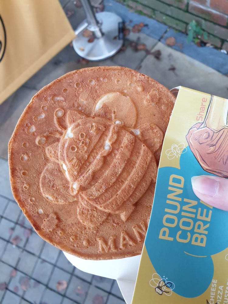 A round sweet bread shaped like a pound coin with a cartoon cat-bee design on it