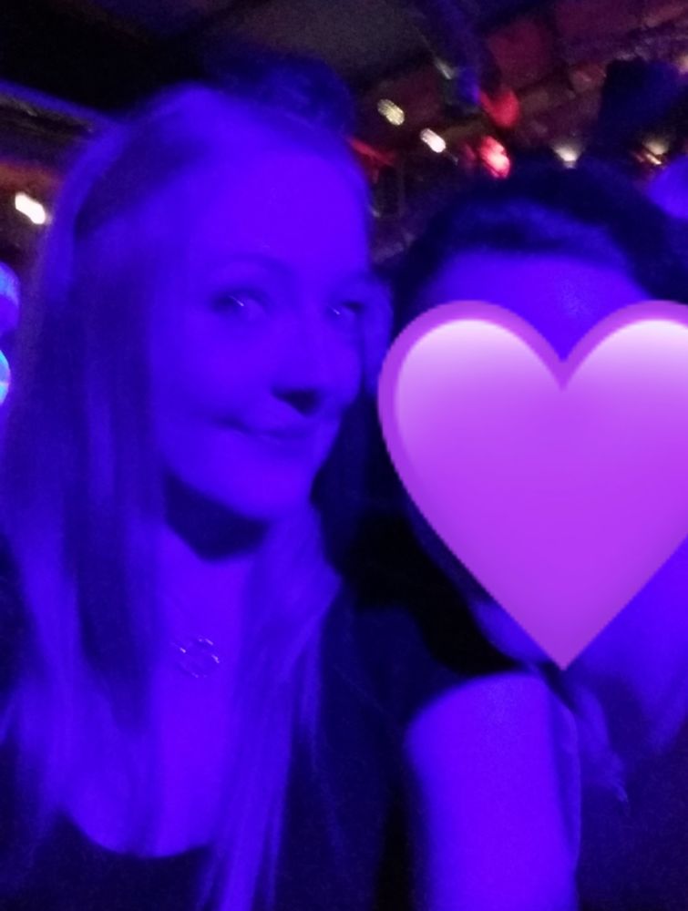Unscharfes Selfie in blauem Licht. Rechts neben mir eine Person verdeckt mit einem lila Herz Emoji.
