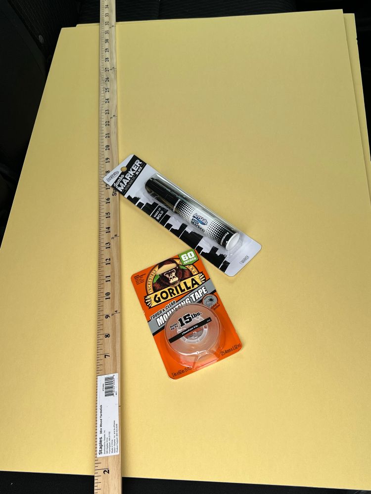 yellow poster board, big black marker, wooden yard stick, roll of clear tape