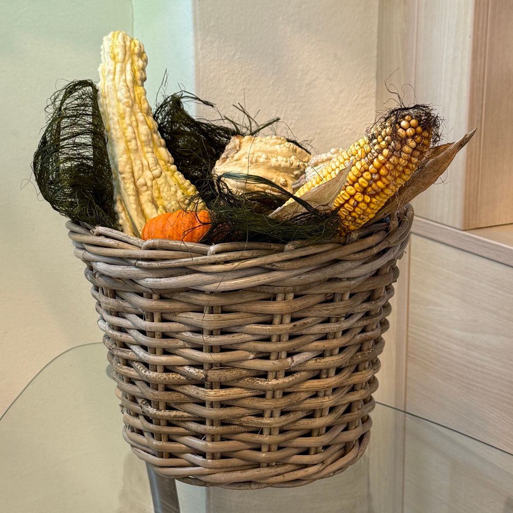 Geflochtener Korb mit Kürbissen, Mais und Dekobändern