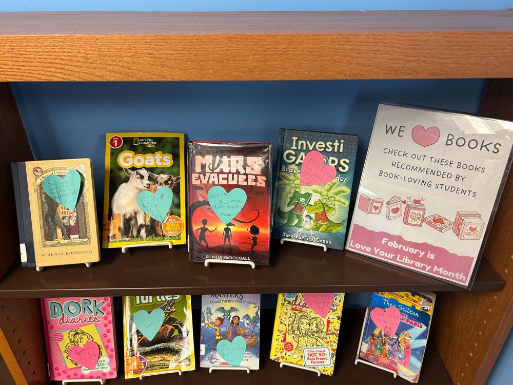 Students leave messages to other readers on heart shaped sticky notes for favorite books