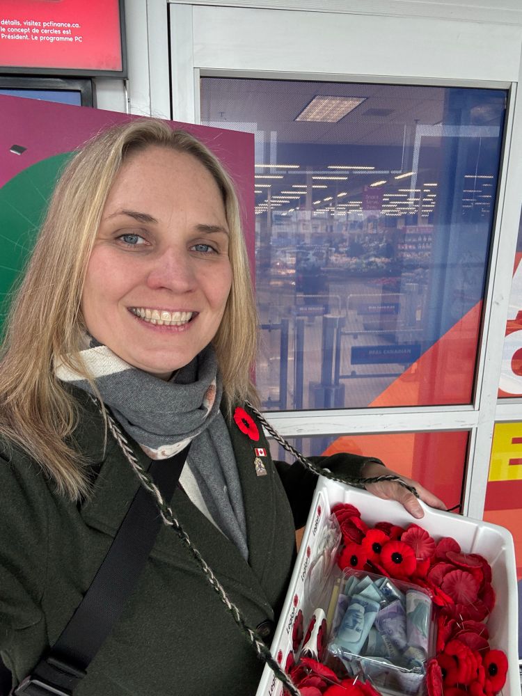 Alison with a poppy tray around her neck at the front of the Superstore entrance doors. 