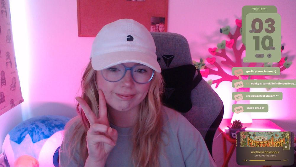 a selfie of oakky. she is smiling and holding up the peace sign whilst wearing a cap