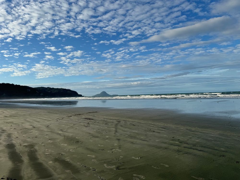 Looking out towards the ocean at low tide in the evening with multiple clouds and blue skies