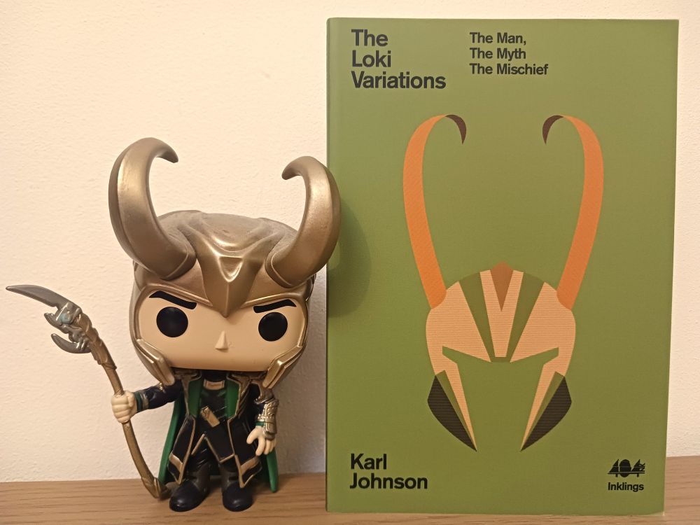A Funko Pop figure of Loki from the Marvel movies mainly coloured gold, green and black, standing next to a green book. The green book has a yellow and orange horned helmet design on the cover. The book is called 'The Loki Variations: The Man, The Myth, The Mischief' written by Karl Johnson and published by 404 Ink.