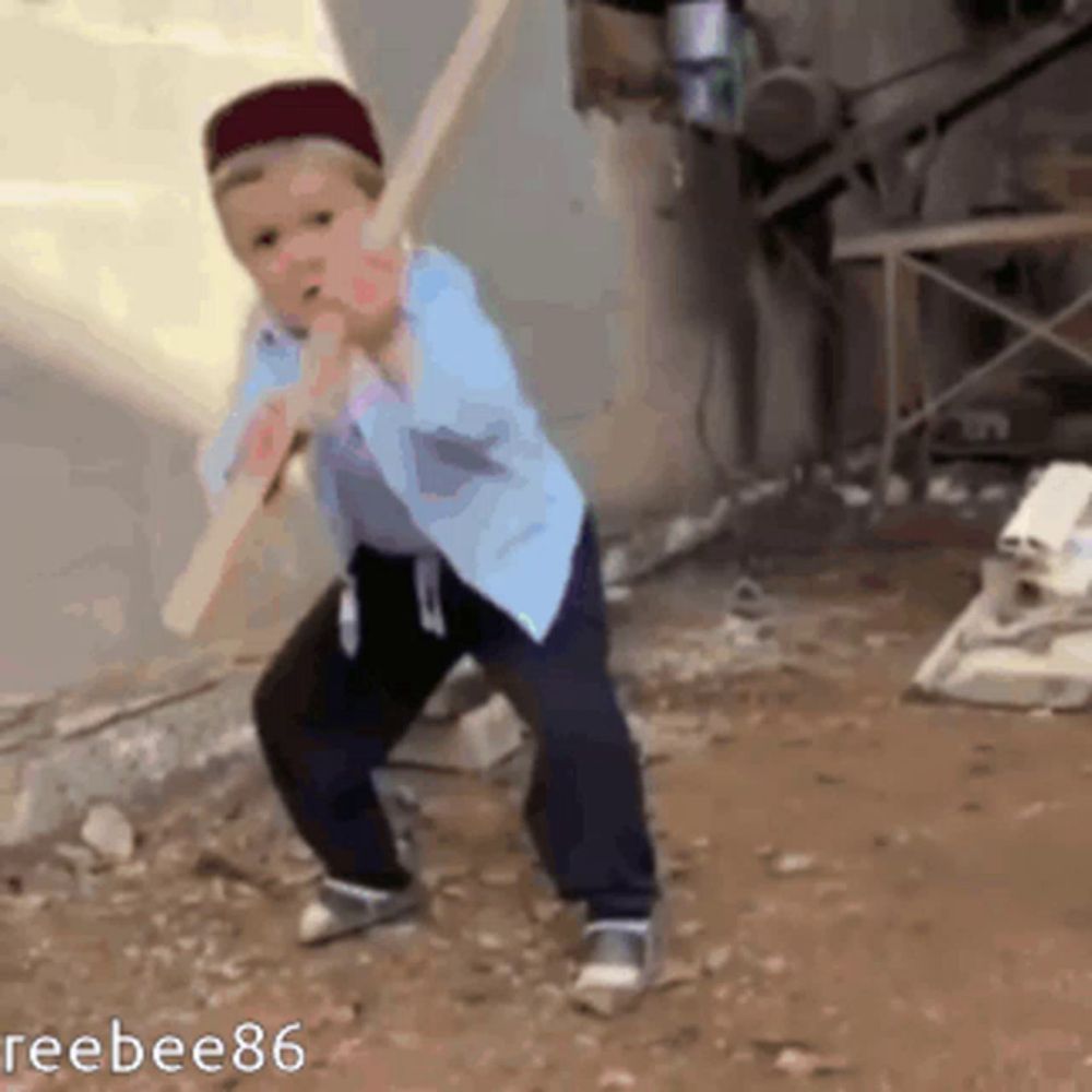 a young boy is holding a large wooden stick in his mouth ..