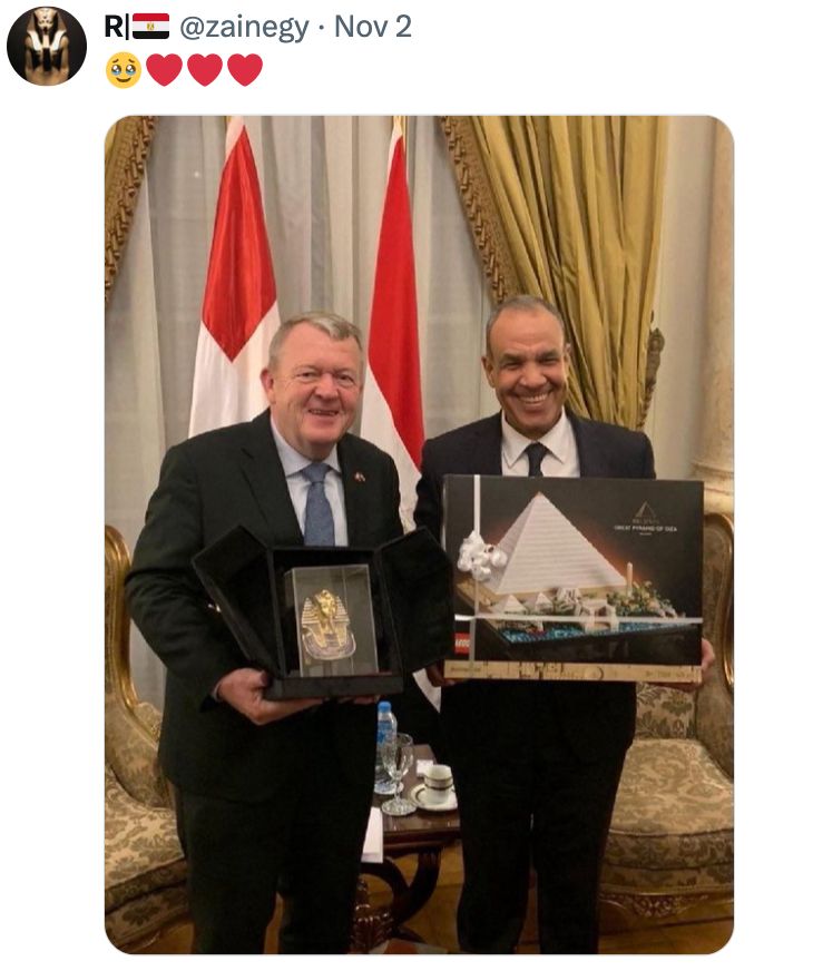 Tweet by @zainegy: captioned "🥹❤️❤️❤️" 
Accompanied by a picture of the Danish Foreign Minister Lars Løkke Rasmussen, holding a miniature replica of the mask of Tutankhamun, and Egyptian Foreign Minister Badr Abdelaty holding a LEGO set of the Great Pyramid of Giza